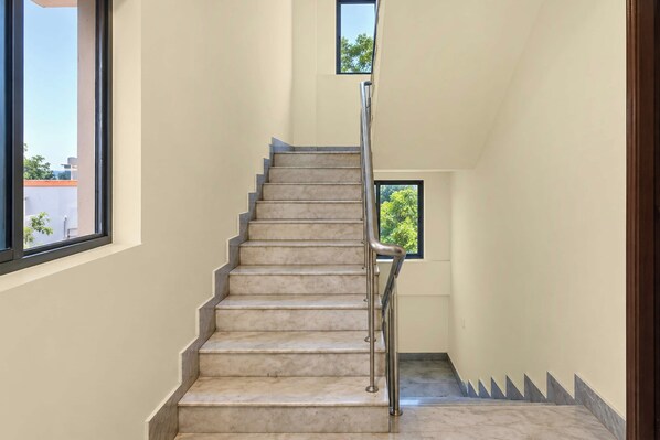 A staircase with a metal handrail, leading to a landing with a window.