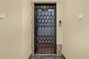 A door with a metal gate, a wall switch, and a thermostat. - Hotel O Biswa Bangla Gate  (Barasat)