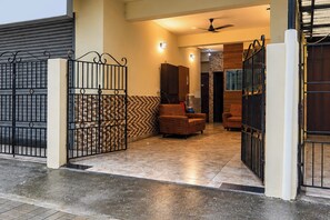 A gated entrance to a property with a tiled floor and two sofas.