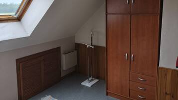 Une chambre avec un plafond en pente, une armoire, un radiateur et une fenêtre.
