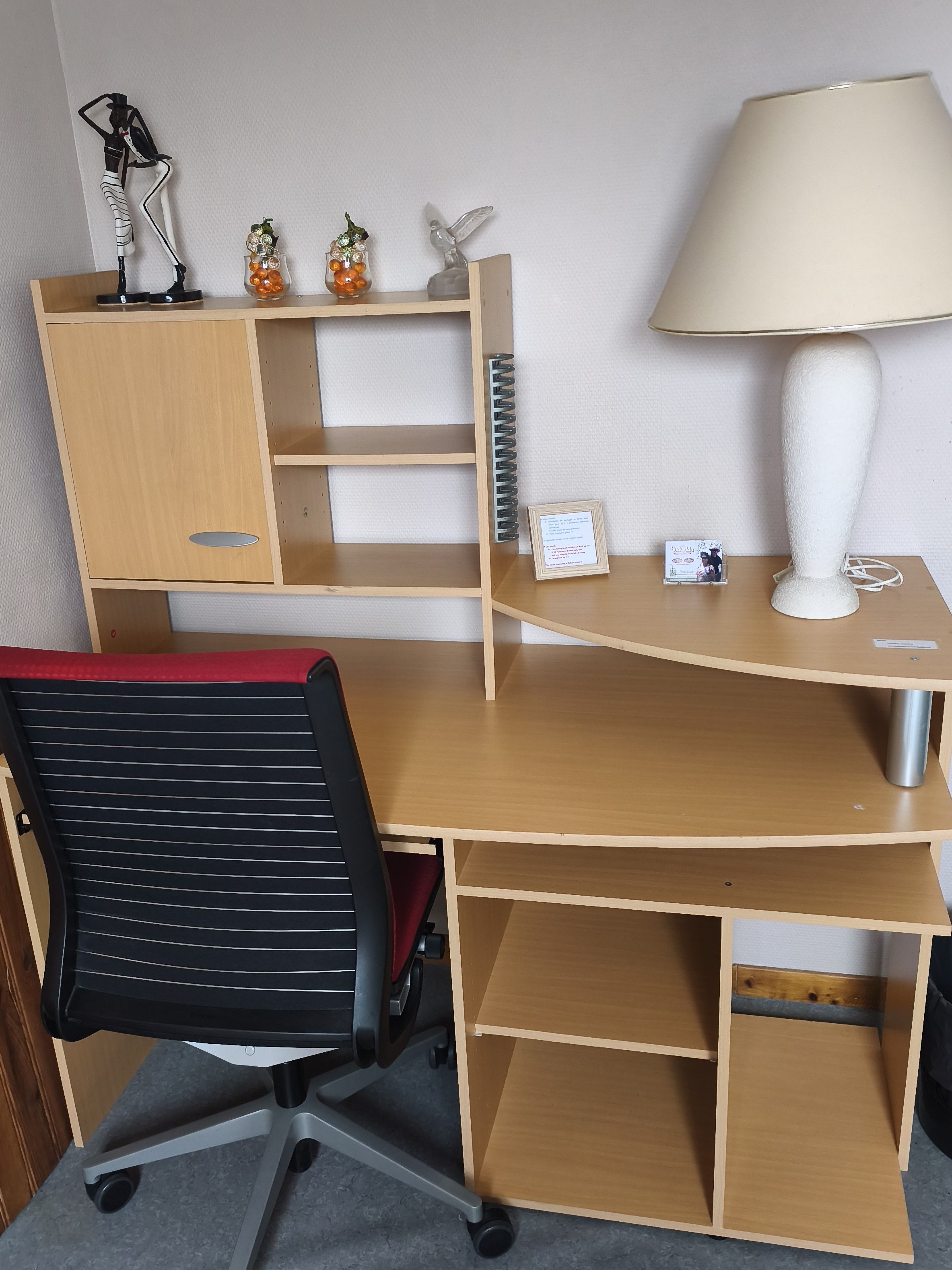 Een houten bureau met een lamp, een stoel en decoratieve voorwerpen.