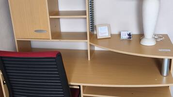 Een houten bureau met een lamp, een stoel en decoratieve voorwerpen.