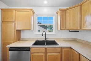 A kitchen with wooden cabinets, a black sink, and a dishwasher.