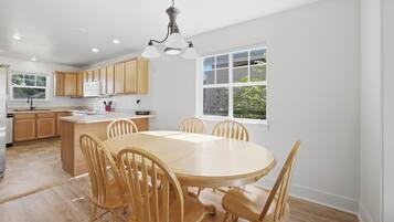 Una cocina moderna con armarios de madera, una isla central y un comedor con seis sillas.