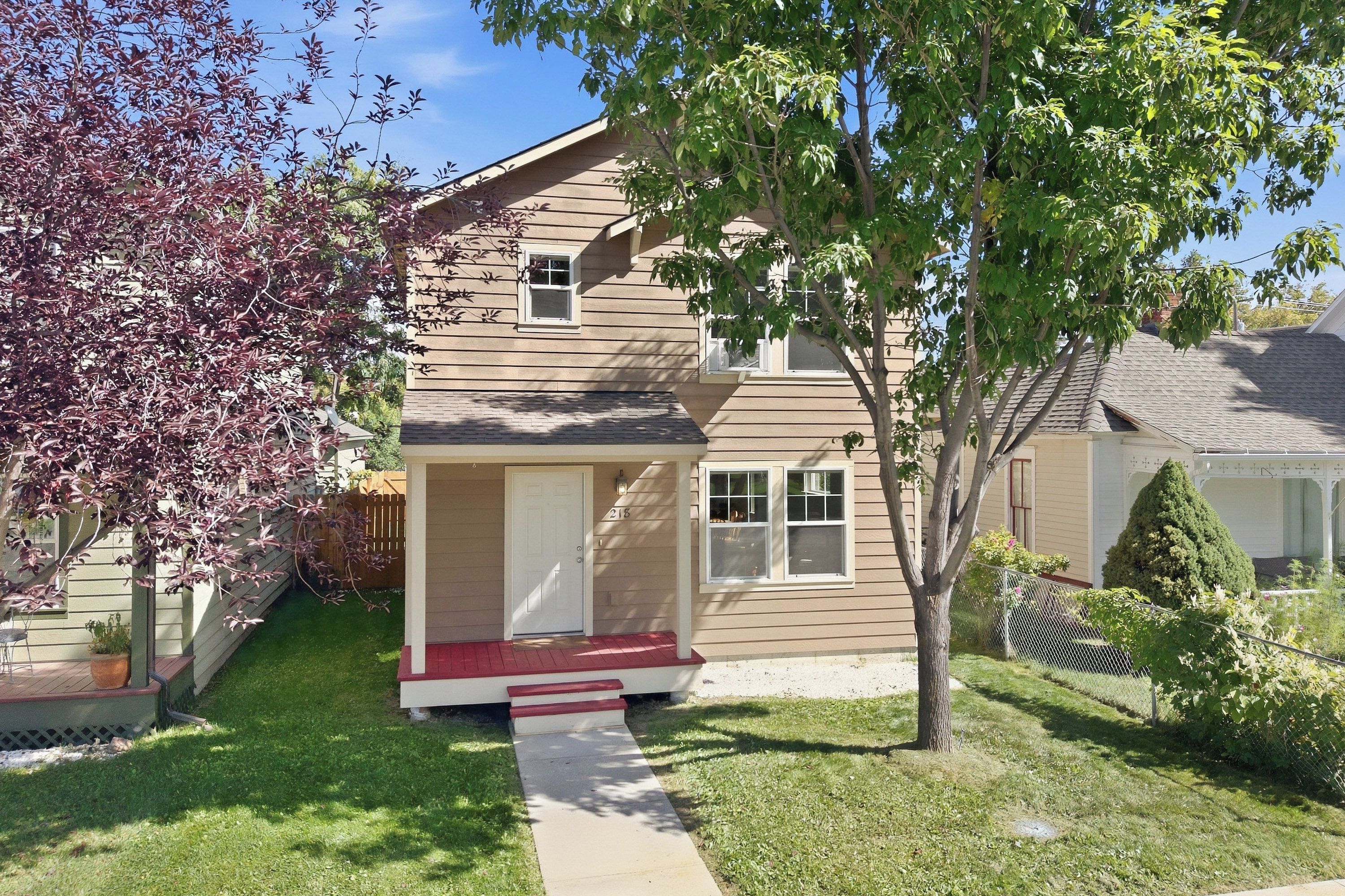 A two-story residential house with a front porch, a small front yard, and a mailbox.