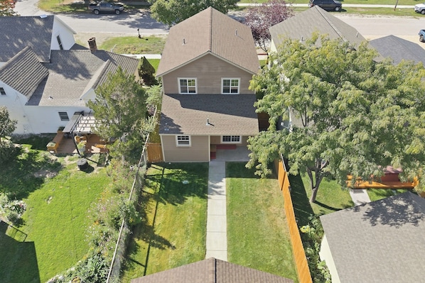 A two-story house with a front yard, a driveway, and a neighboring property.