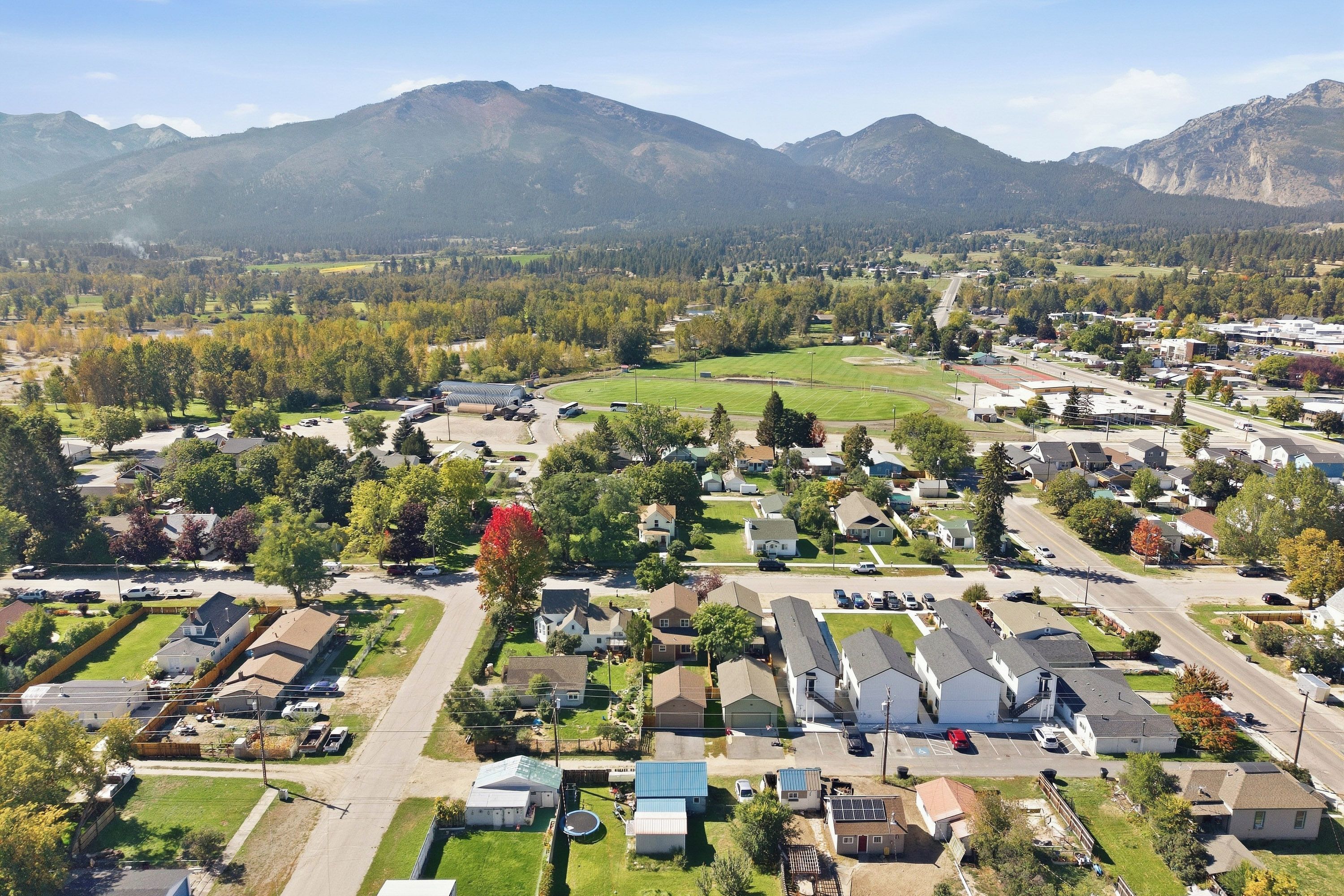 A residential area with houses, roads, and a large green field.