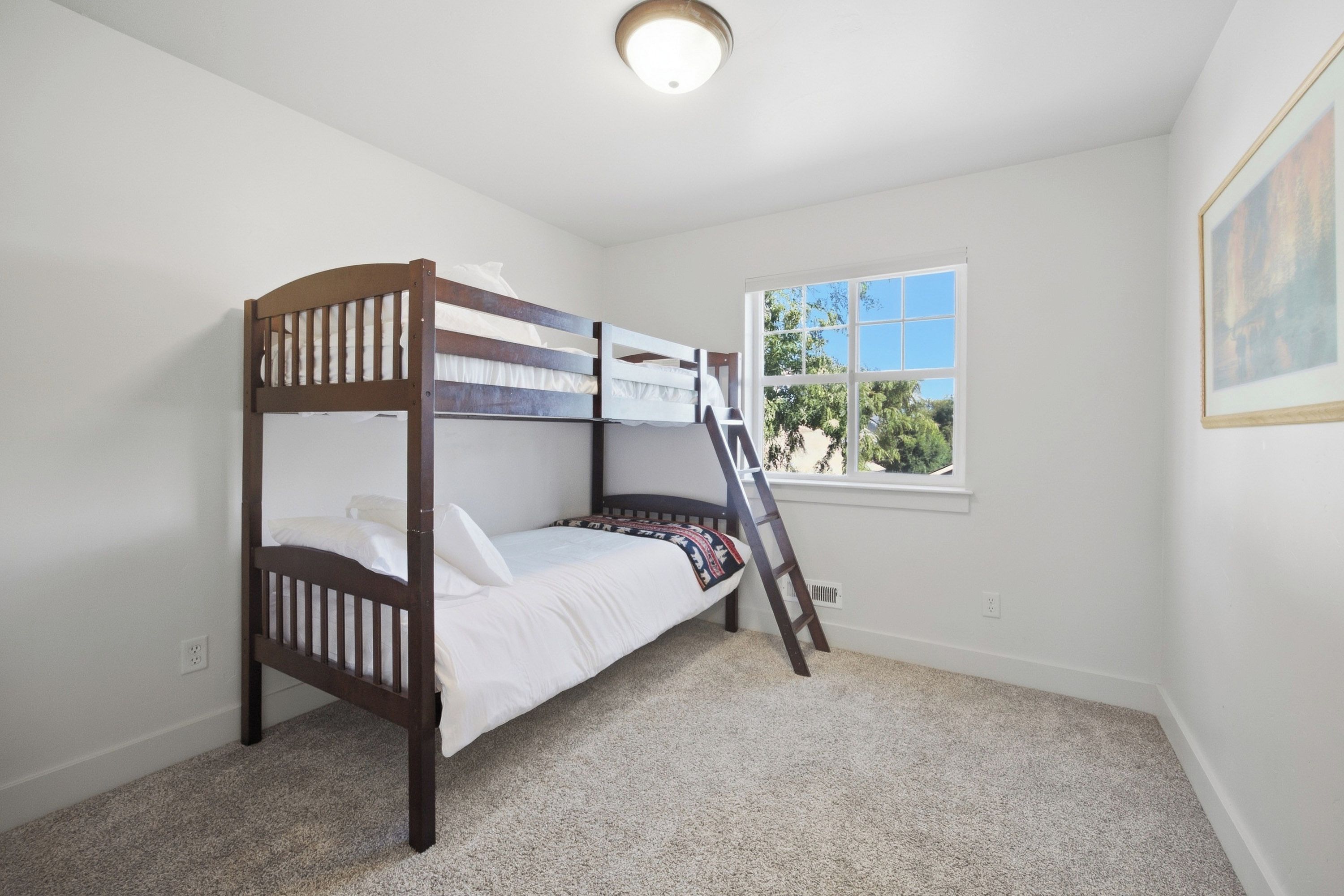 A bunk bed room with a window and a ladder.