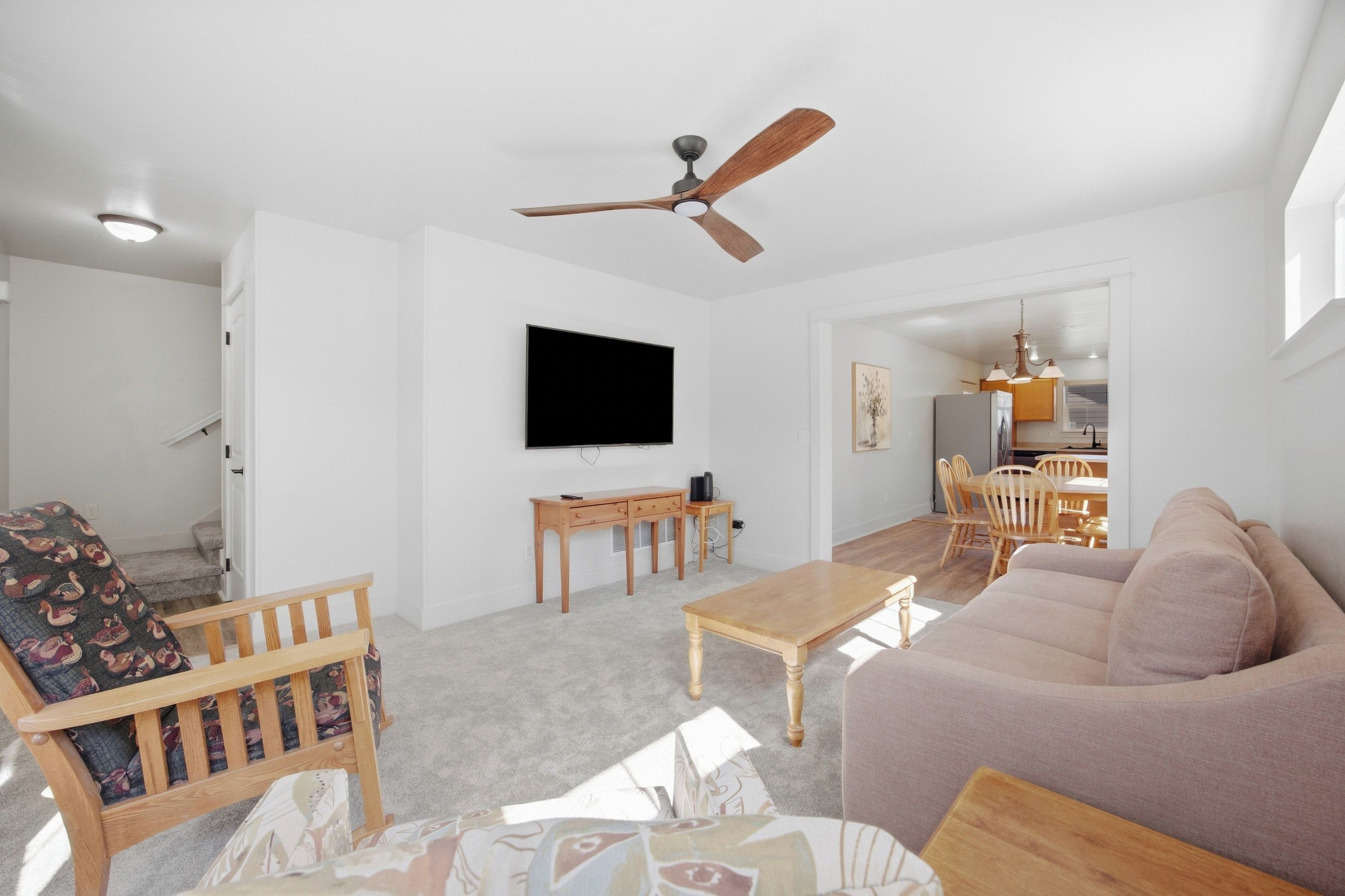 Un salon avec un canapé, une table basse, un téléviseur et un ventilateur de plafond.