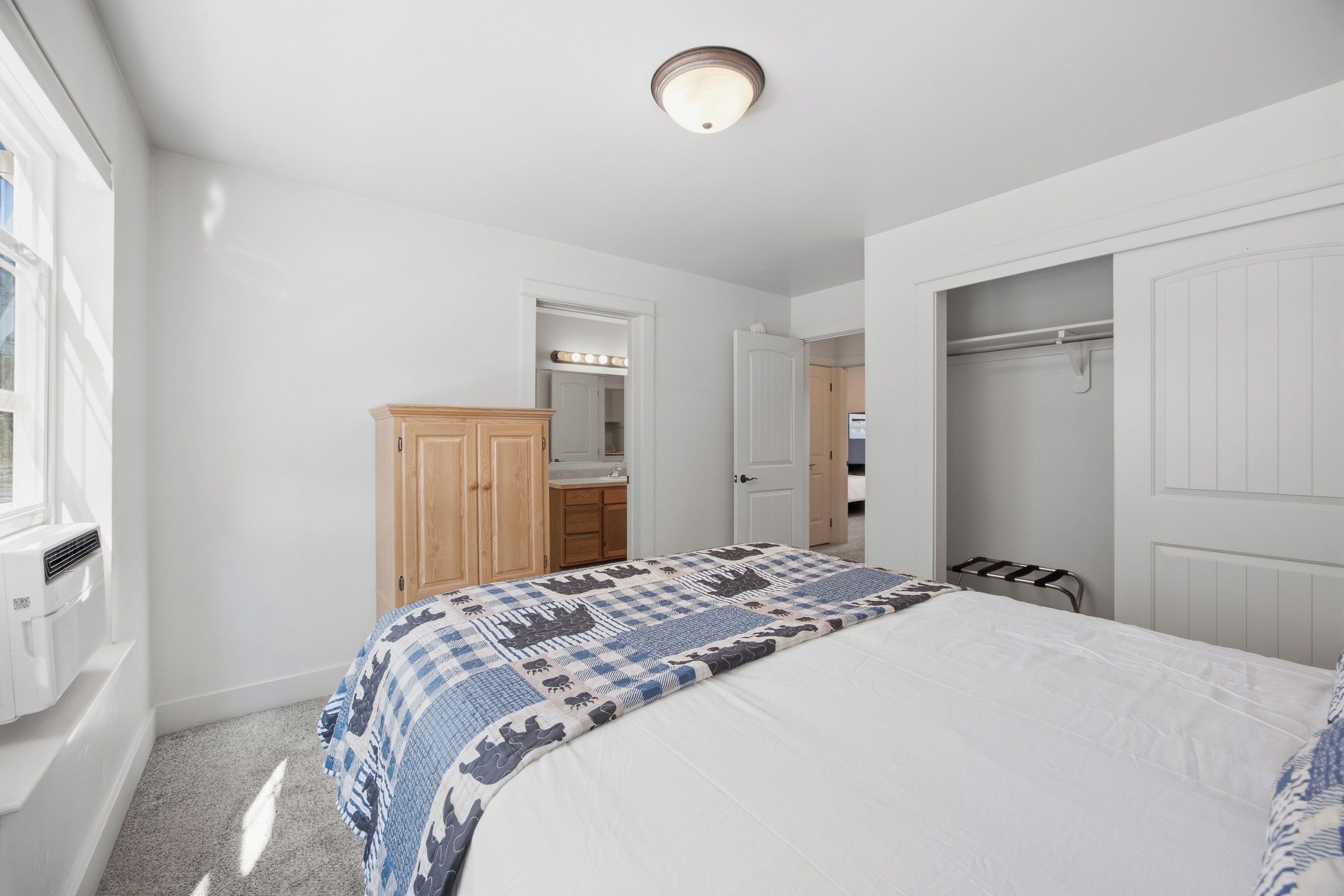 A bedroom with a bed, a wardrobe, a mirror, and a door leading to a bathroom.