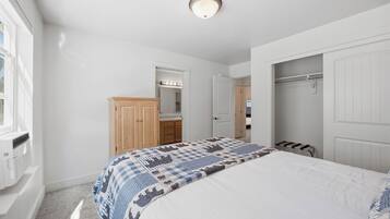 A bedroom with a bed, a wardrobe, a mirror, and a door leading to a bathroom.