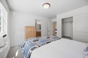 A bedroom with a bed, a wardrobe, a mirror, and a door leading to a bathroom.