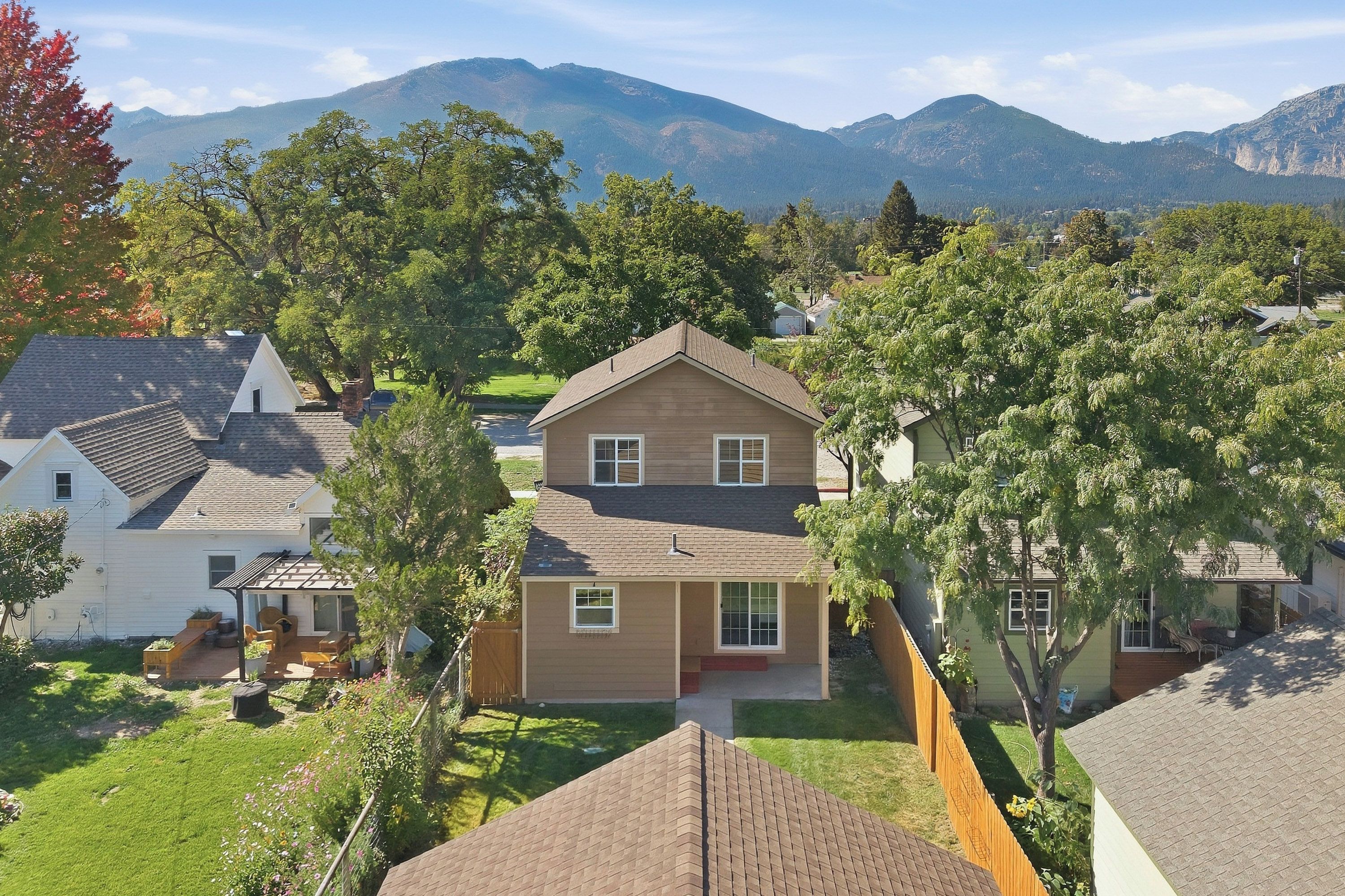 A residential area with houses, a well-maintained lawn, and a mountain range in the background.