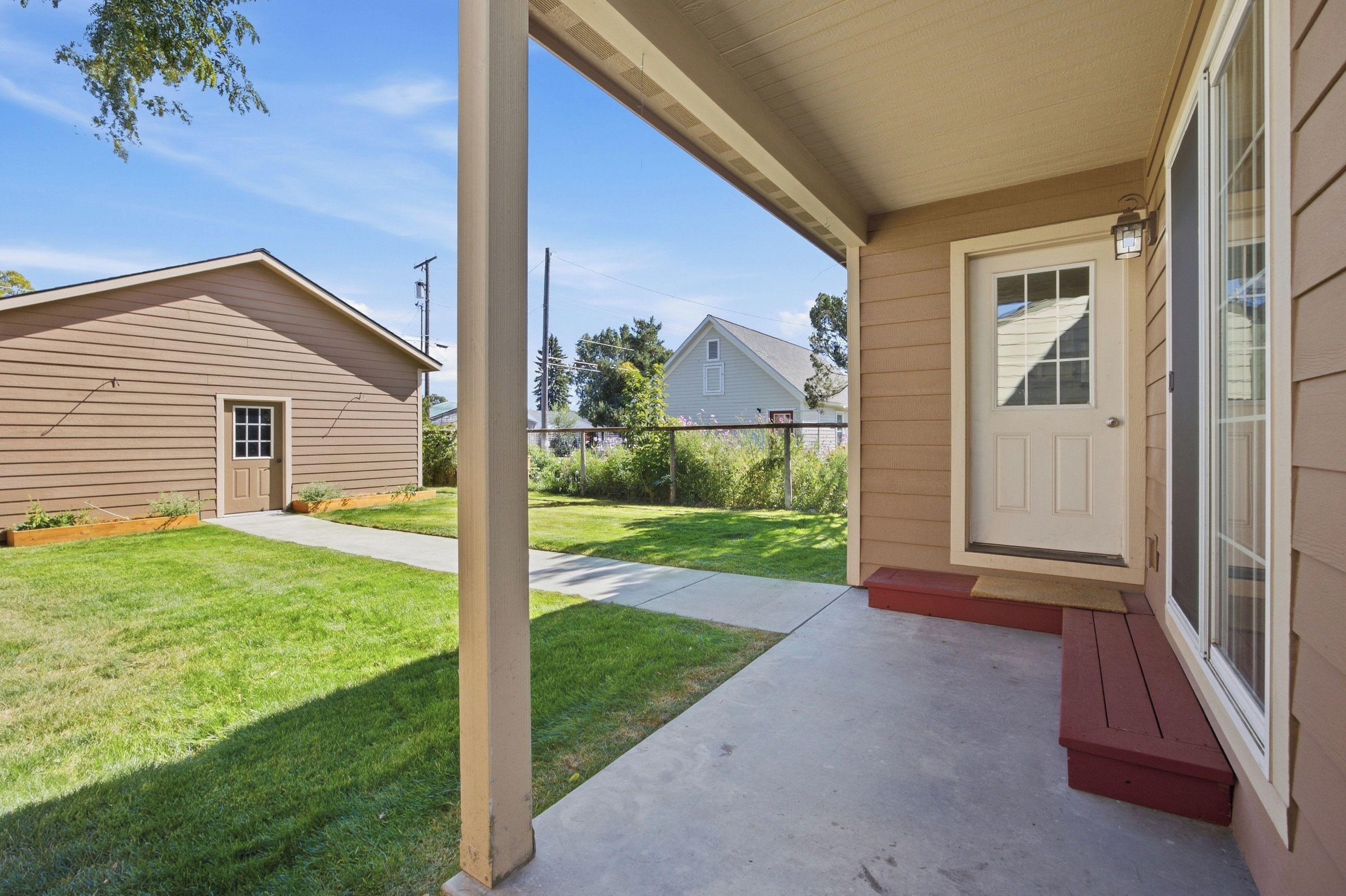 A residential property with a covered porch, a front door, and a well-maintained lawn.