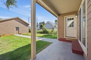 A residential property with a covered porch, a front door, and a well-maintained lawn.