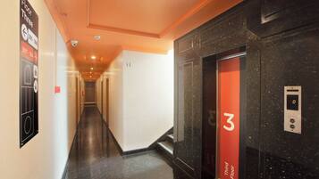 A hotel corridor with a third-floor elevator, a security camera, and a fire alarm.