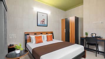 Una habitación de hotel con una cama, una mesita de noche con una planta, un escritorio con una silla y un armario.