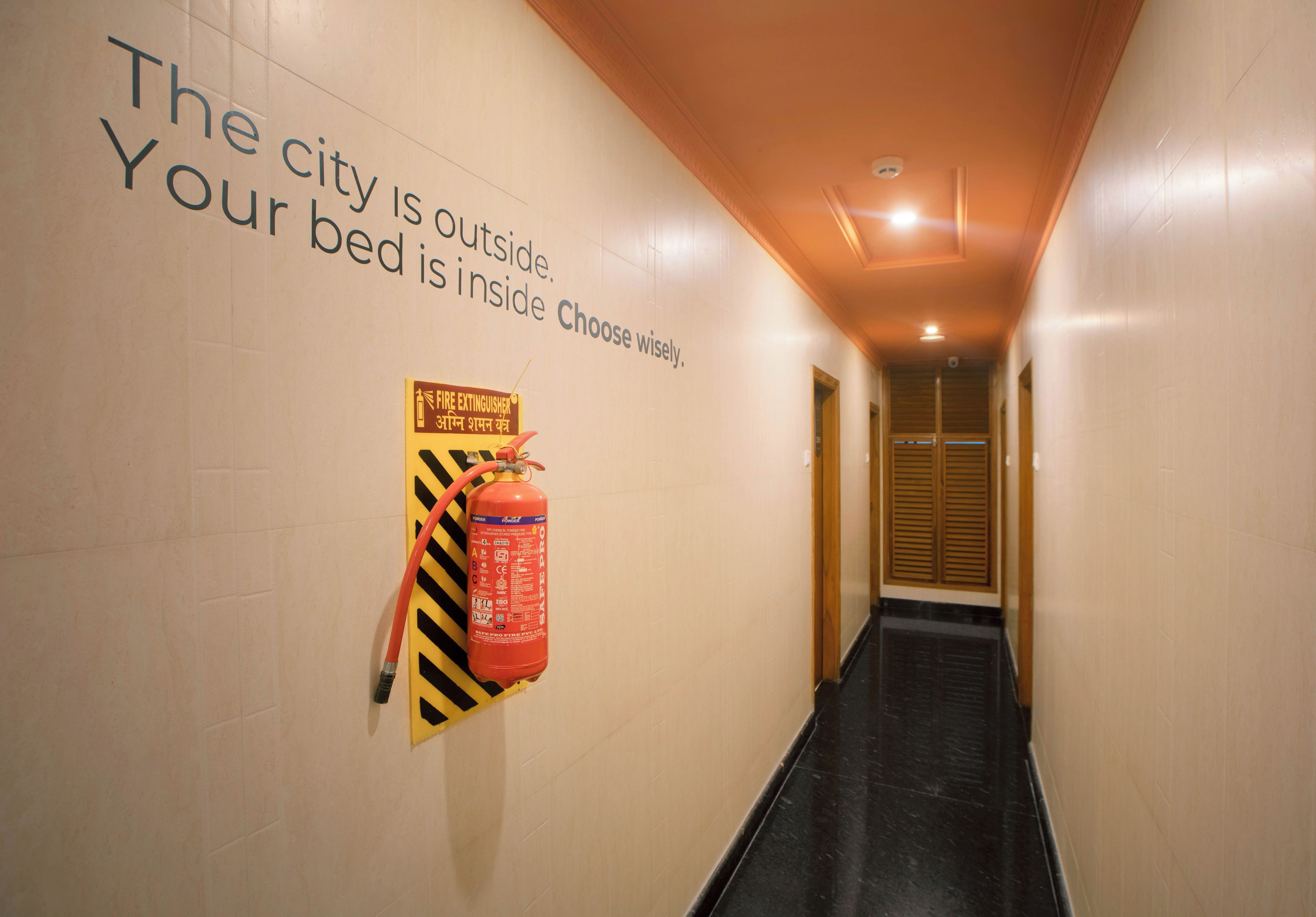 Un pasillo con un extintor instalado en la pared y un cartel con indicaciones de seguridad.