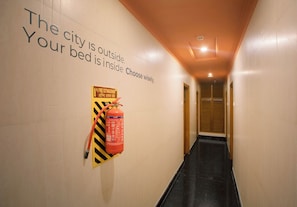 A hallway with a fire extinguisher mounted on the wall and a sign with safety instructions.