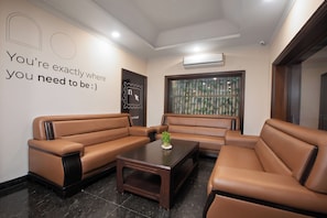A modern waiting area with leather sofas, a coffee table, and a decorative wall with a motivational quote.