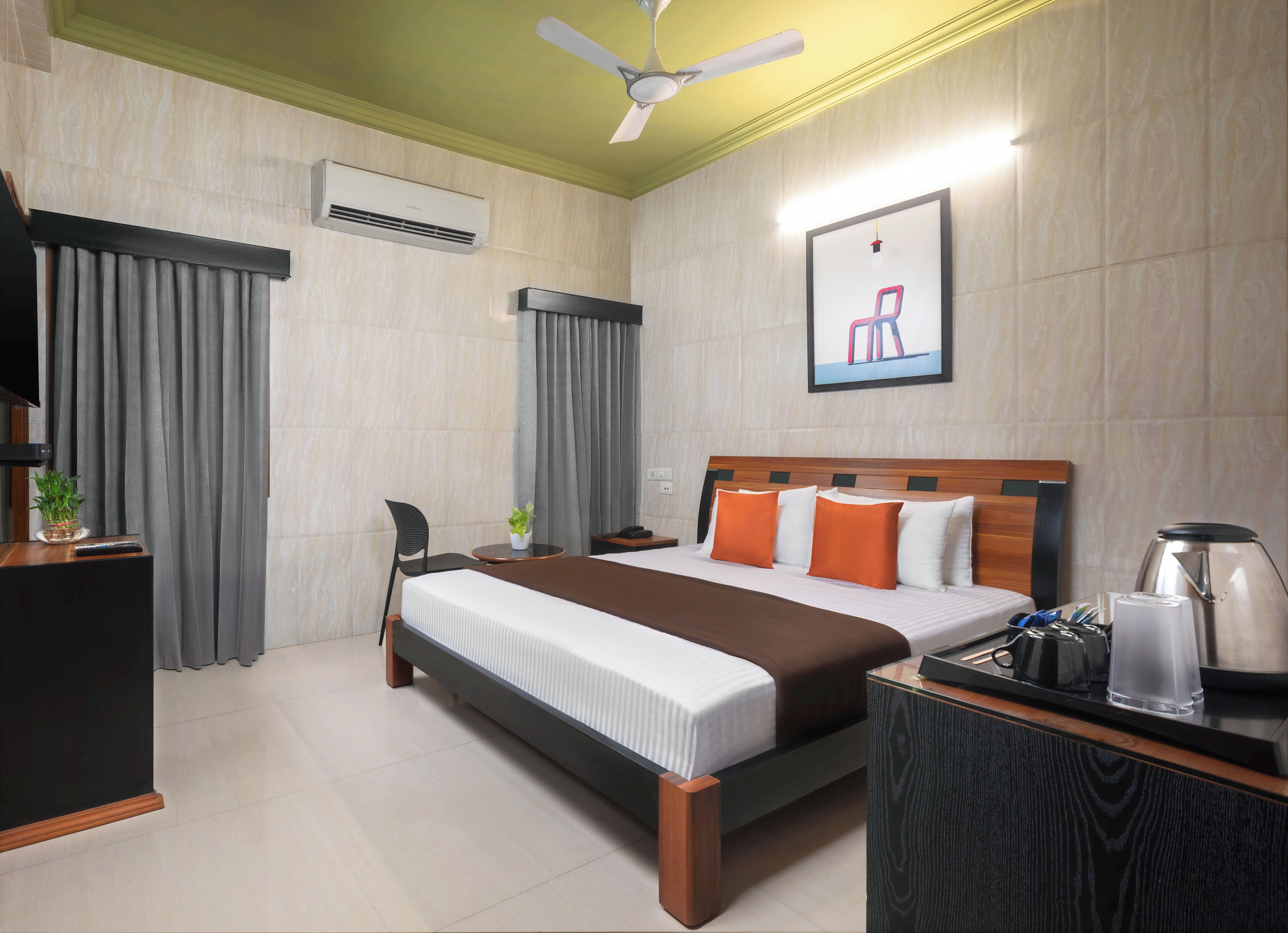A hotel room with a bed, a desk, a chair, a coffee maker, and a ceiling fan.