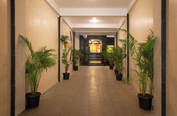 A hallway with potted plants, a tiled floor, and a staircase leading to an interior space.