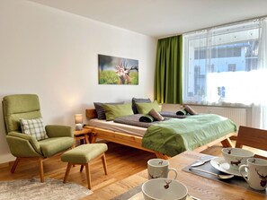 A room with a bed, a chair, a table with a cup and saucer, and a painting on the wall. - A cozy getaway at the Hirschzauber vacation rental with mountain views in the heart of Oberstdorf (Oberstdorf)
