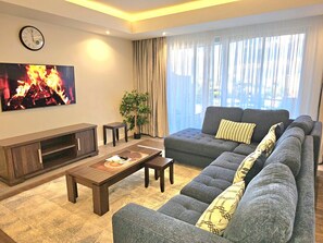 A modern living room with a sofa, coffee table, TV, and a plant. - Cozy 1-bedroom apartment in serene Nairobi with fitness room (Nairobi)