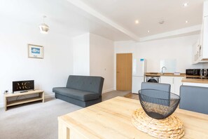 Ein modernes Wohnzimmer mit einem grauen Sofa, einem Holztisch und einem Fernsehschrank.