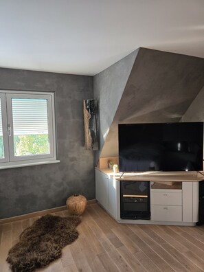 Un salon moderne doté d’un téléviseur à écran plat, d’une cheminée et d’une grande fenêtre.