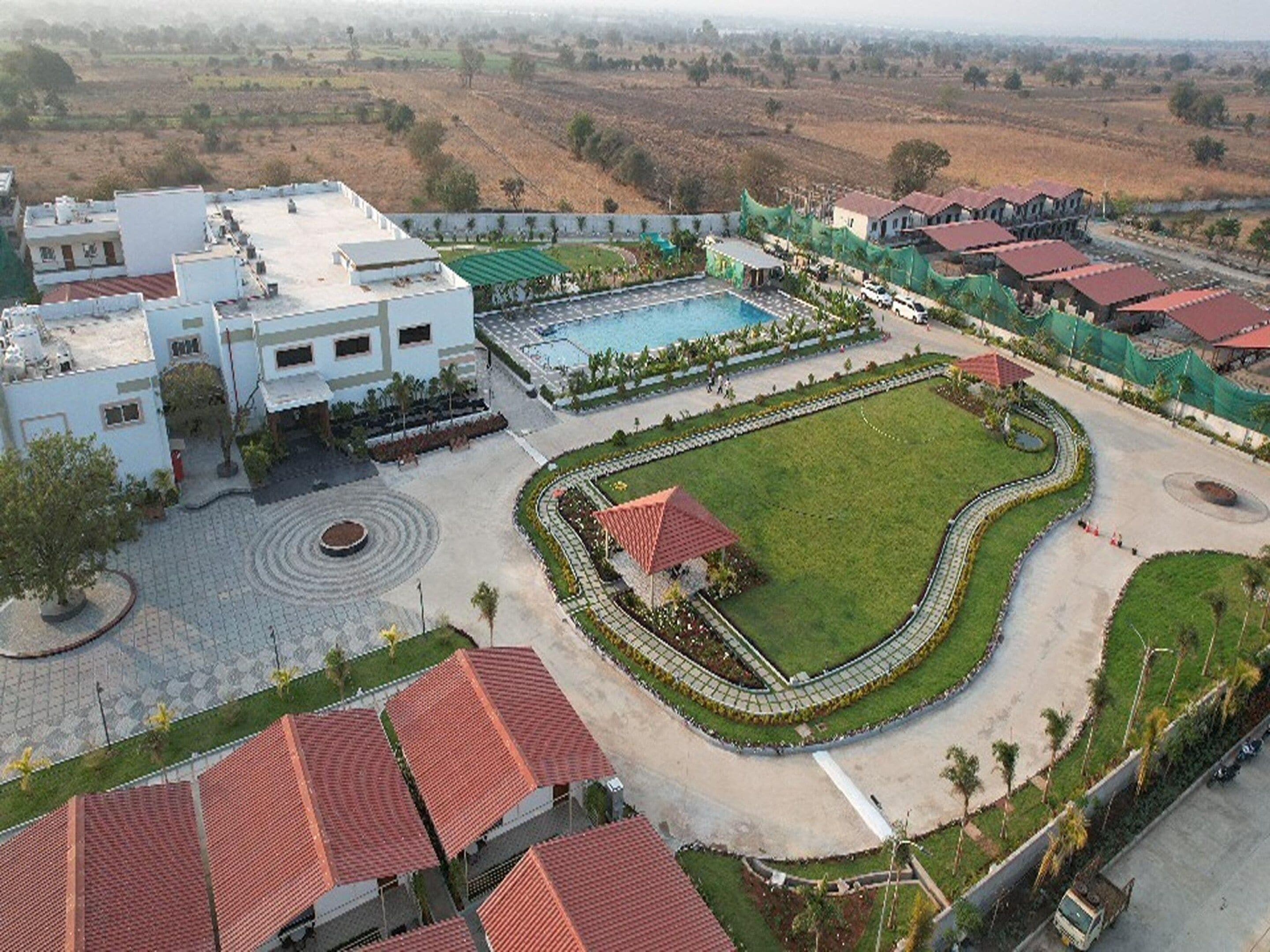 Un hotel con piscina, jardín ajardinado y zona de estacionamiento.