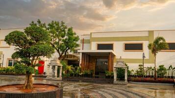 A courtyard with a fountain, trees, and a building with a modern design.
