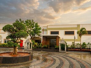 Um pátio com uma fonte, árvores e um edifício de design moderno.