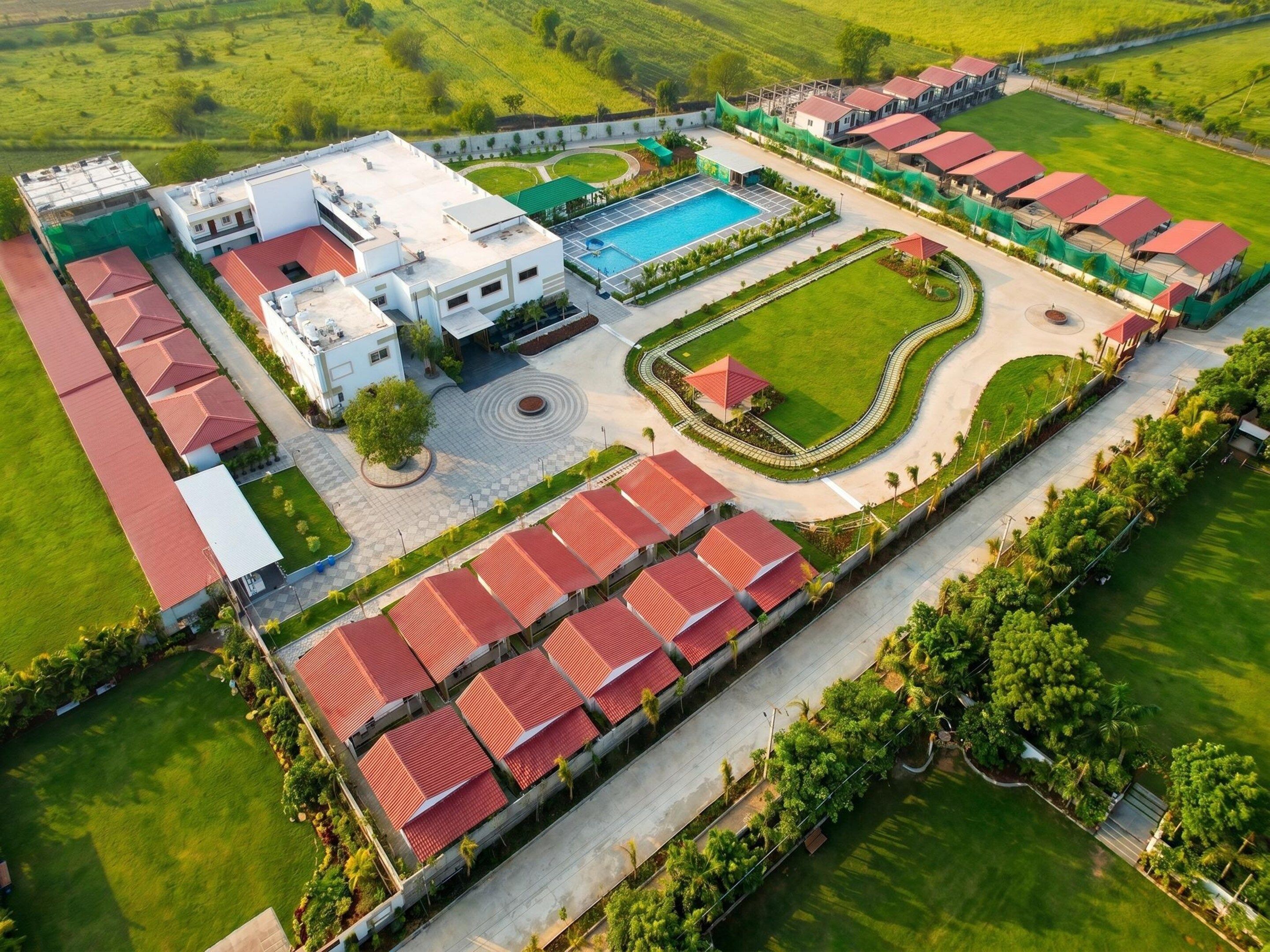 Un grand complexe hôtelier comprenant plusieurs bâtiments, une piscine et des jardins bien entretenus.
