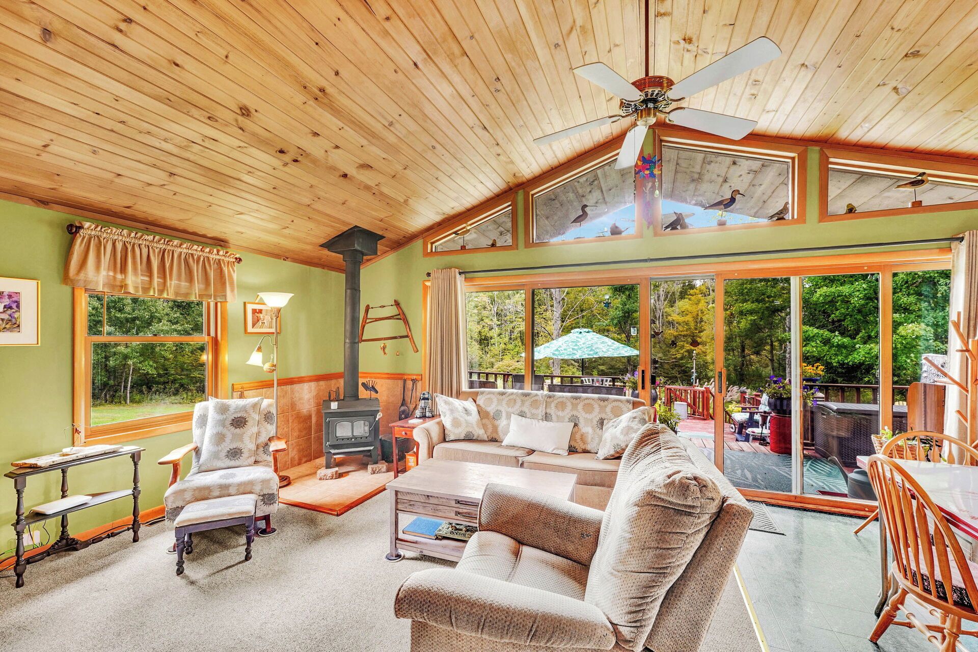 Un intérieur chaleureux avec une cheminée, un coin salon et de grandes fenêtres donnant sur l’extérieur.