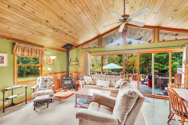 A cozy interior with a fireplace, seating area, and large windows offering views of the outdoors.
