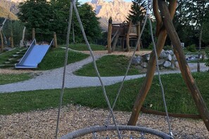 Ein Spielplatz mit Rutsche, Schaukeln und einer Kletterkonstruktion.
