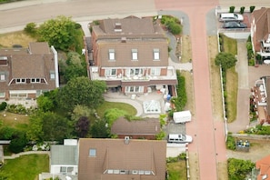 A residential area with multiple houses, a central courtyard, and a white van parked in front. - Beach Villa Atlantic App. 03 (Norderney)