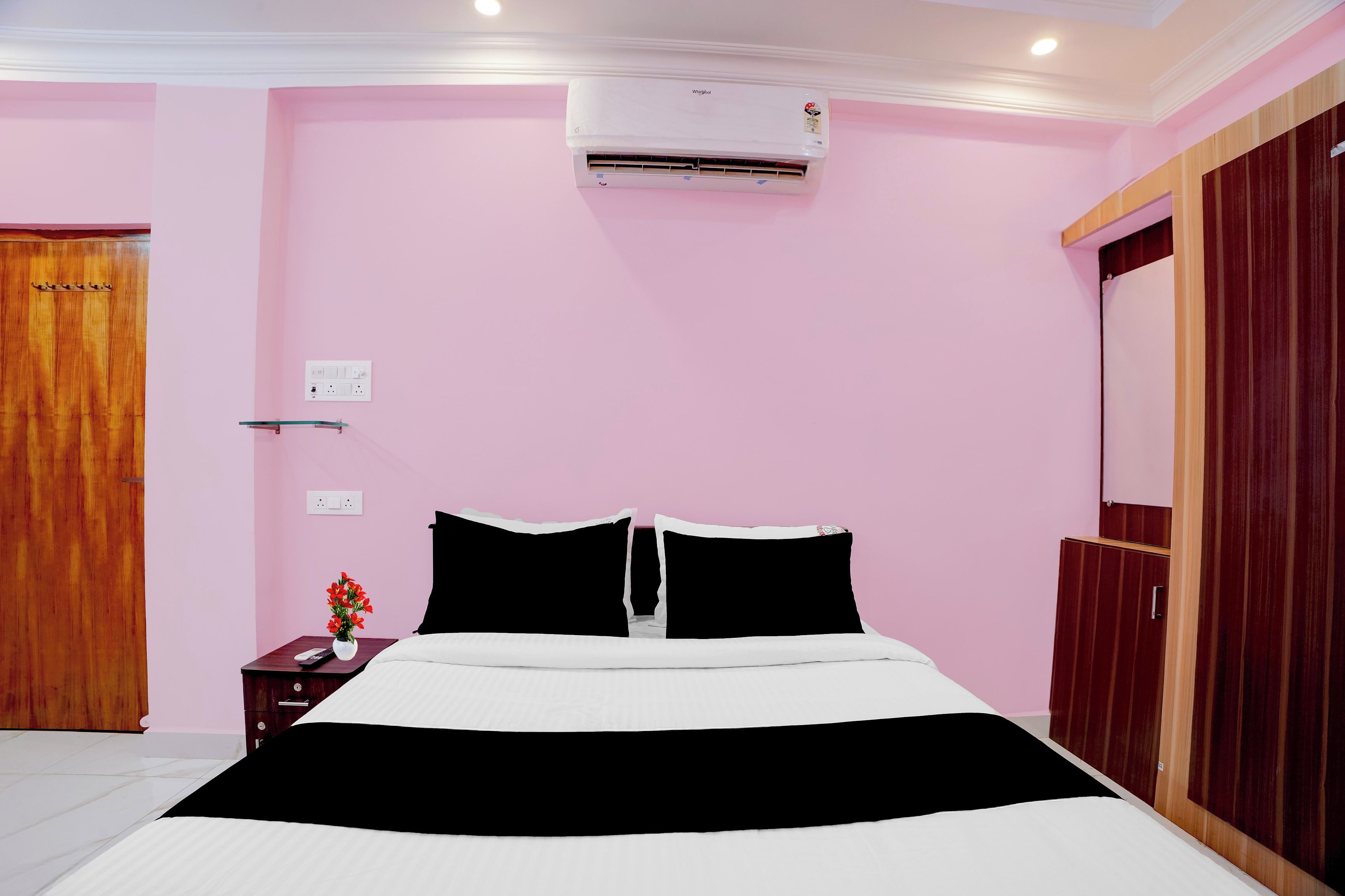 Una habitación de hotel con cama, mesita de noche y equipo de aire acondicionado.
