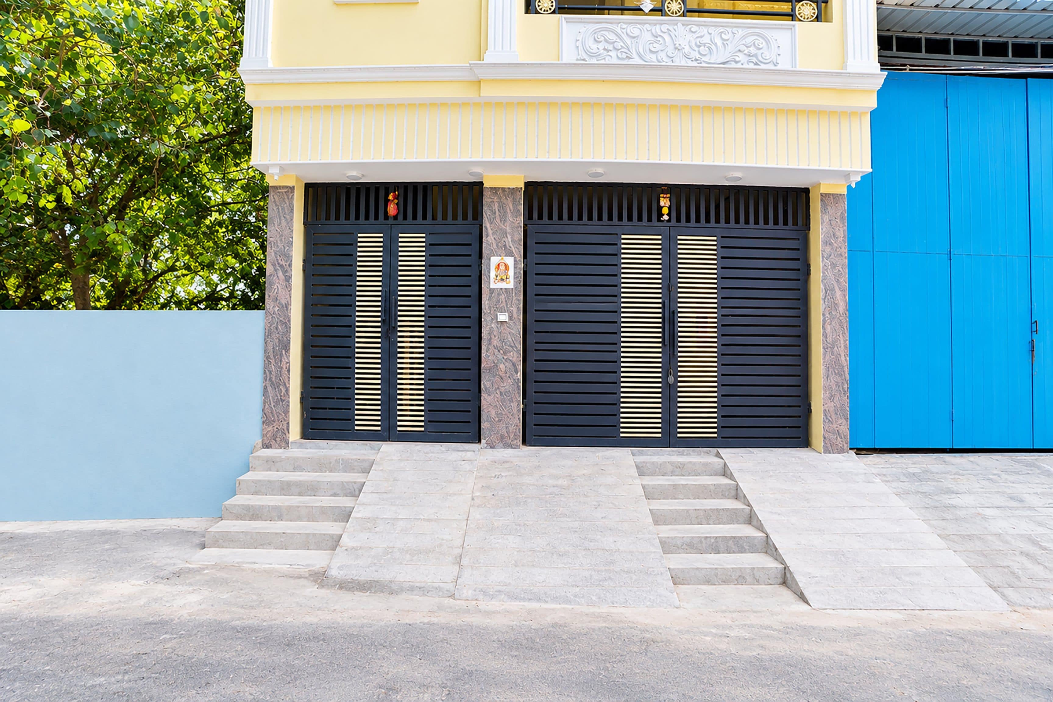 Um edifício com entrada de dois andares, apresentando um conjunto de degraus que levam a uma porta com ripas horizontais.