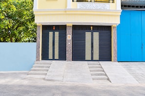 Um edifício com entrada de dois andares, apresentando um conjunto de degraus que levam a uma porta com ripas horizontais.