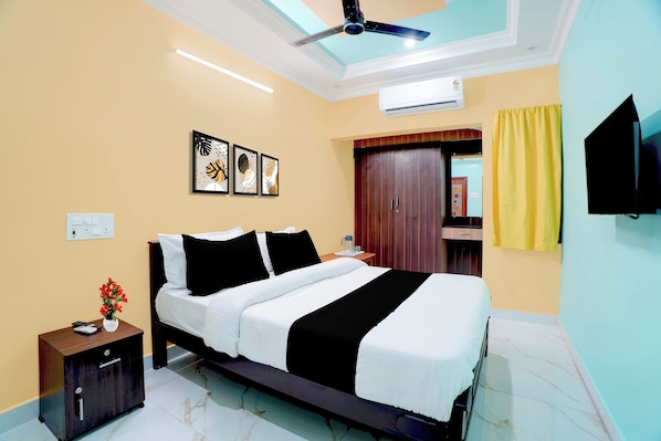 Quarto de hotel com cama, mesa de cabeceira, obras de arte, guarda-roupa e ventilador de teto.