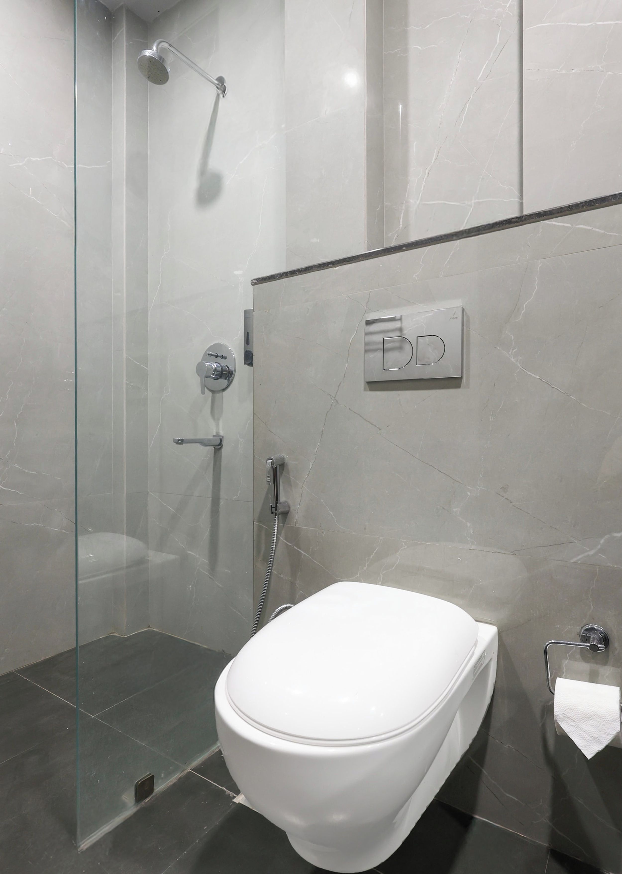 Uma casa de banho moderna com cabine de duche envidraçada, sanita e porta-toalhas.