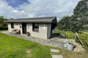 Uma casa moderna de dois andares com fachada de tijolos, telhado plano e pequena varanda.