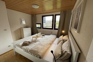 A bedroom with a bed, bedside table, and a window with curtains. - Holiday home in Meschede with swimming pool (Meschede)