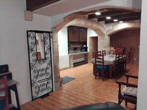 An interior with a dining area, kitchen, and a decorative metal gate. - La Tour Au Comté Vacation Rental. Experience the authentic lifestyle, from a 15th-century tower to farm life. (Charency)