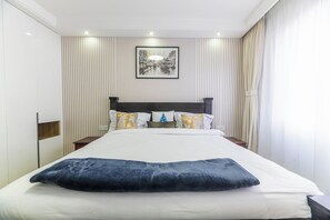 Ein Hotelzimmer mit einem großen Bett, einem Kopfteil, einem Nachttisch, einem Wandbild und einem Fenster mit Vorhängen.