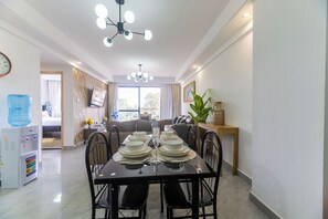 A dining area with a table set for four, a water dispenser, and a ceiling light fixture. - Cozy 2-bedroom apartment in beautiful Westlands Nairobi (Westlands, Nairobi, Nairobi)