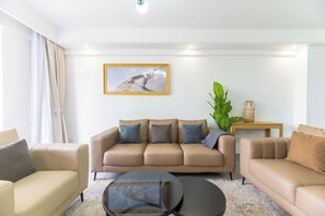 A modern living room with a beige sofa set, a round coffee table, and a large abstract painting on the wall. - Cozy 2-bedroom apartment in beautiful Westlands Nairobi (Westlands, Nairobi, Nairobi)