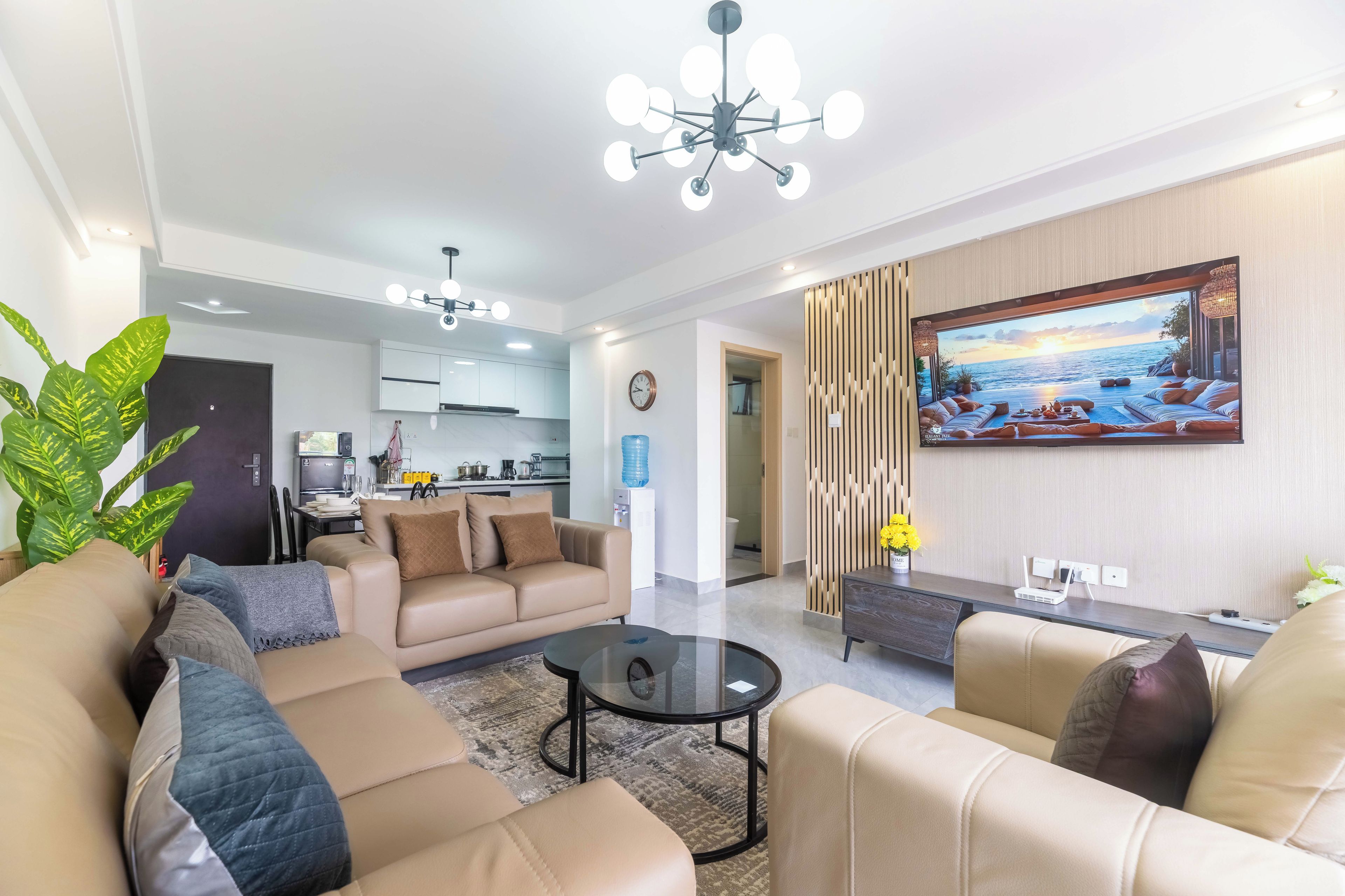 Una sala de estar moderna con un conjunto de sofá, una mesa de centro y un televisor montado en la pared.